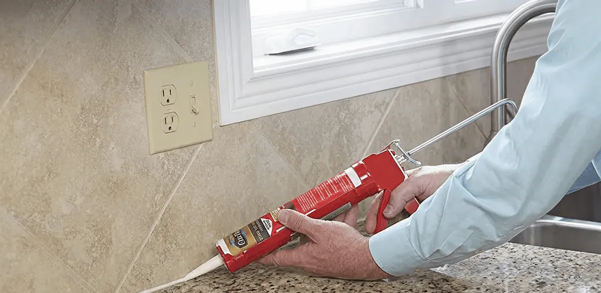 Handyman applying caulk along a kitchen backsplash and countertop seam in Tallahassee, FL