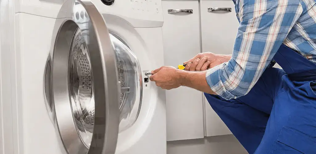 Handyman repairing a clothes dryer and checking electrical connections in Tallahassee, FL