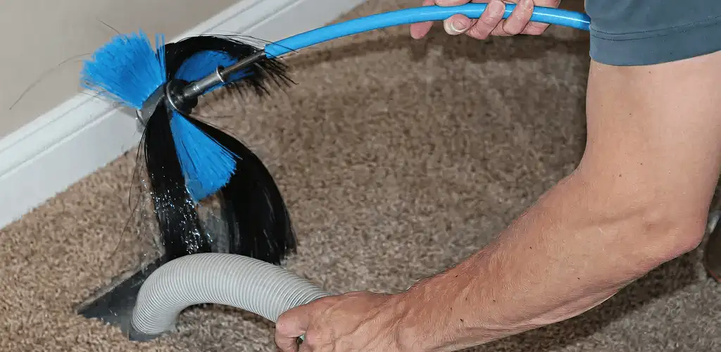 Dryer vent cleaning technician brushing lint from a vent line in Tallahassee, FL