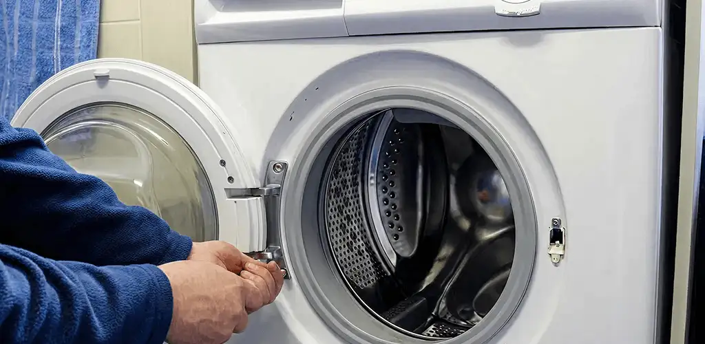 Washing machine repair handyman checking a front-load washer door and latch in Tallahassee, FL
