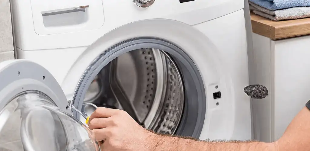 Handyman repairing a front-load washing machine and inspecting the drum in Tallahassee, FL