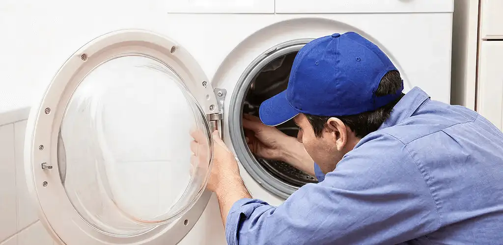 Washing machine repair handyman inspecting a front-load washer drum in Tallahassee, FL