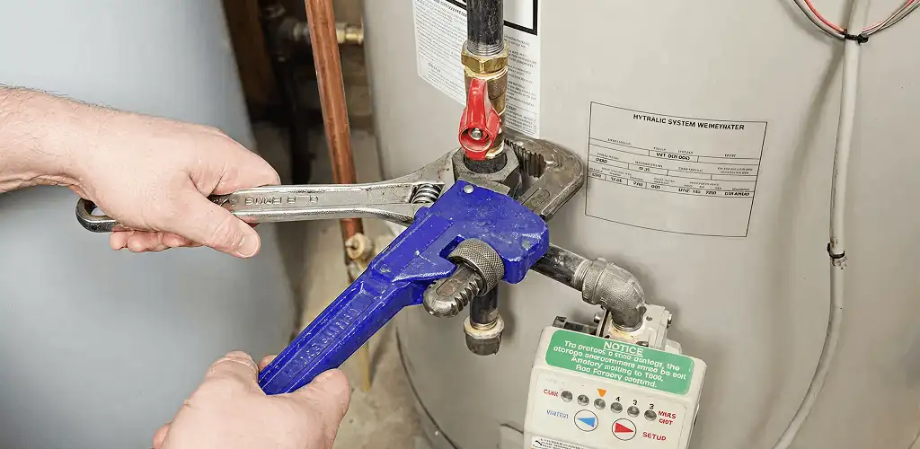 Water heater repair technician tightening the shutoff valve and supply line in Tallahassee, FL